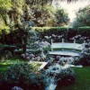 A breathtaking garden area with a bench surrounded by white flowers  