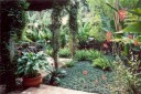 A patio area within a garden surrounded by lush greeneries and flowers